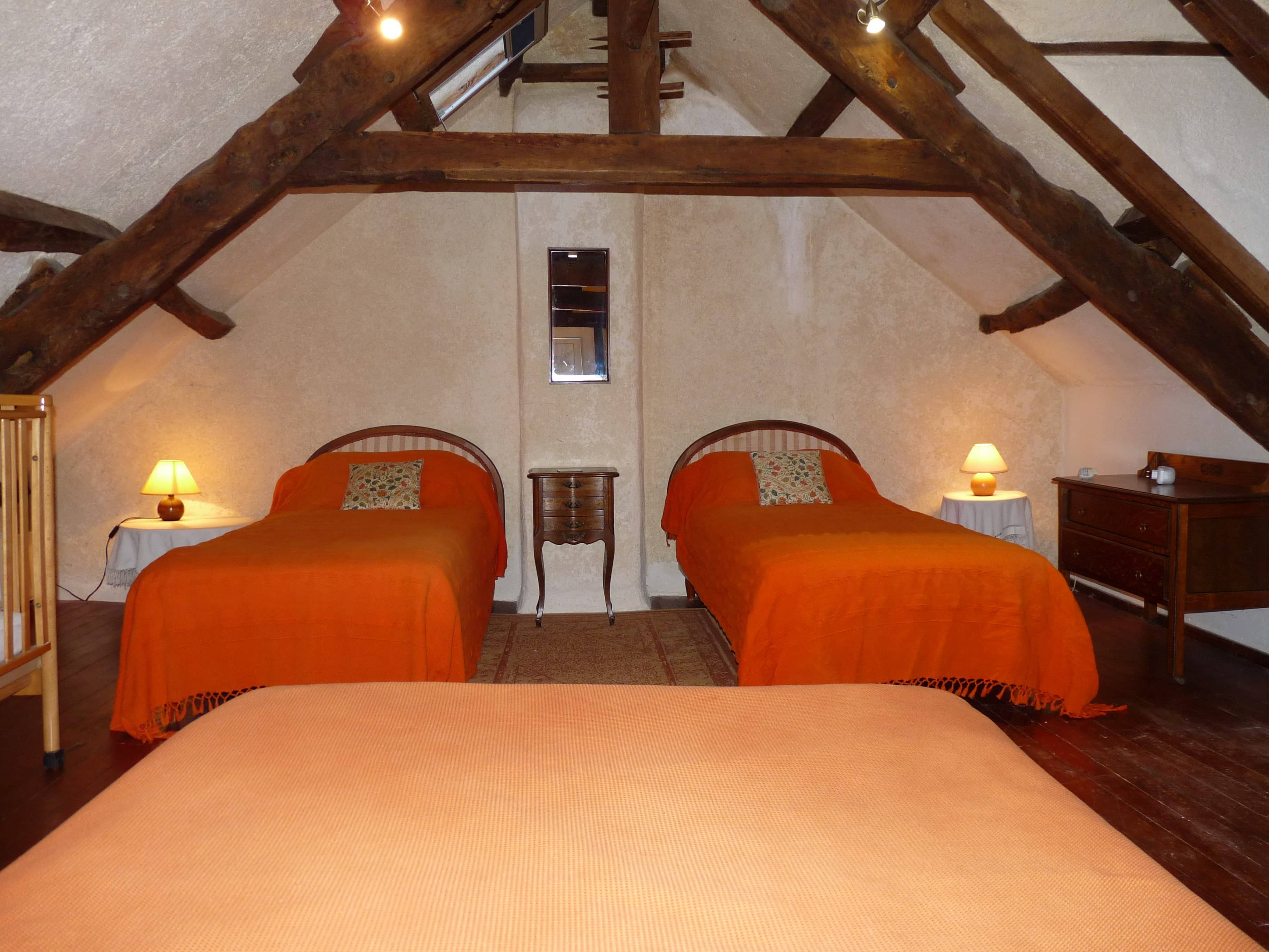 Spacious and comfortable bedroom of La Julerie cottage in Brittany, France, with a king-size bed, elegant rustic decor, a stone fireplace, and a panoramic view of the surrounding countryside. Perfect for a peaceful night's sleep after a day of sightseeing in the Brittany region.